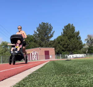 Neely Gracey with son in stroller on a track. 